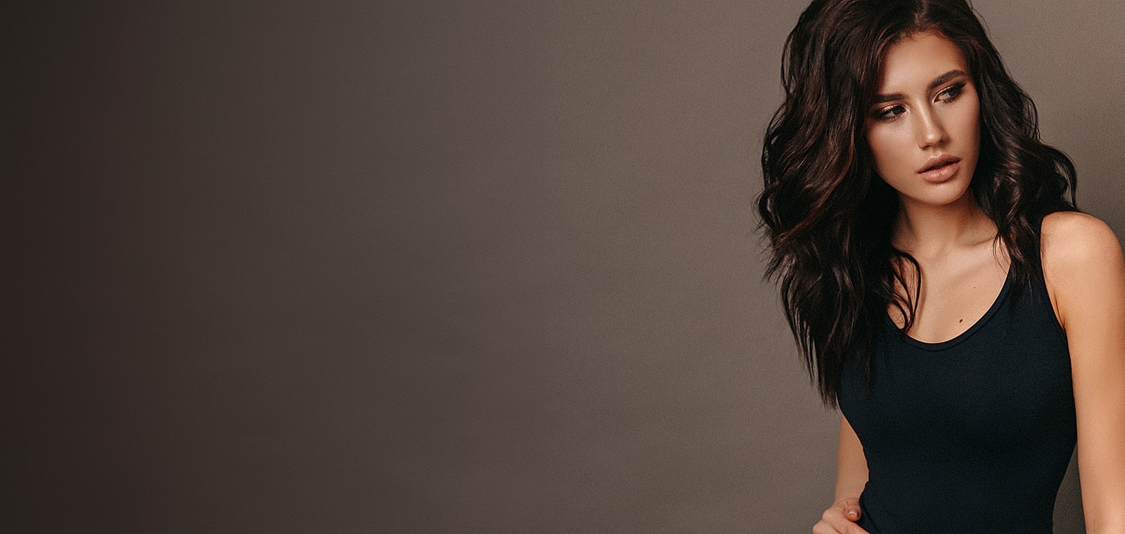 Model with long hair against a dark background.