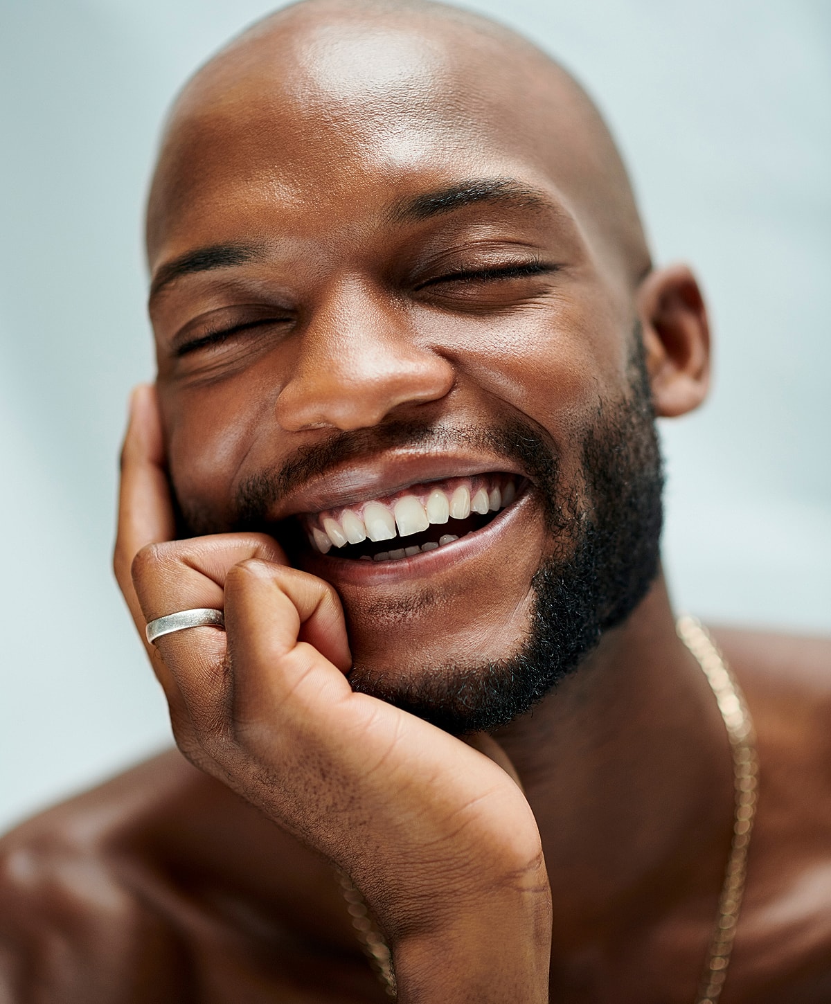 Smiling man touching face joyfully.