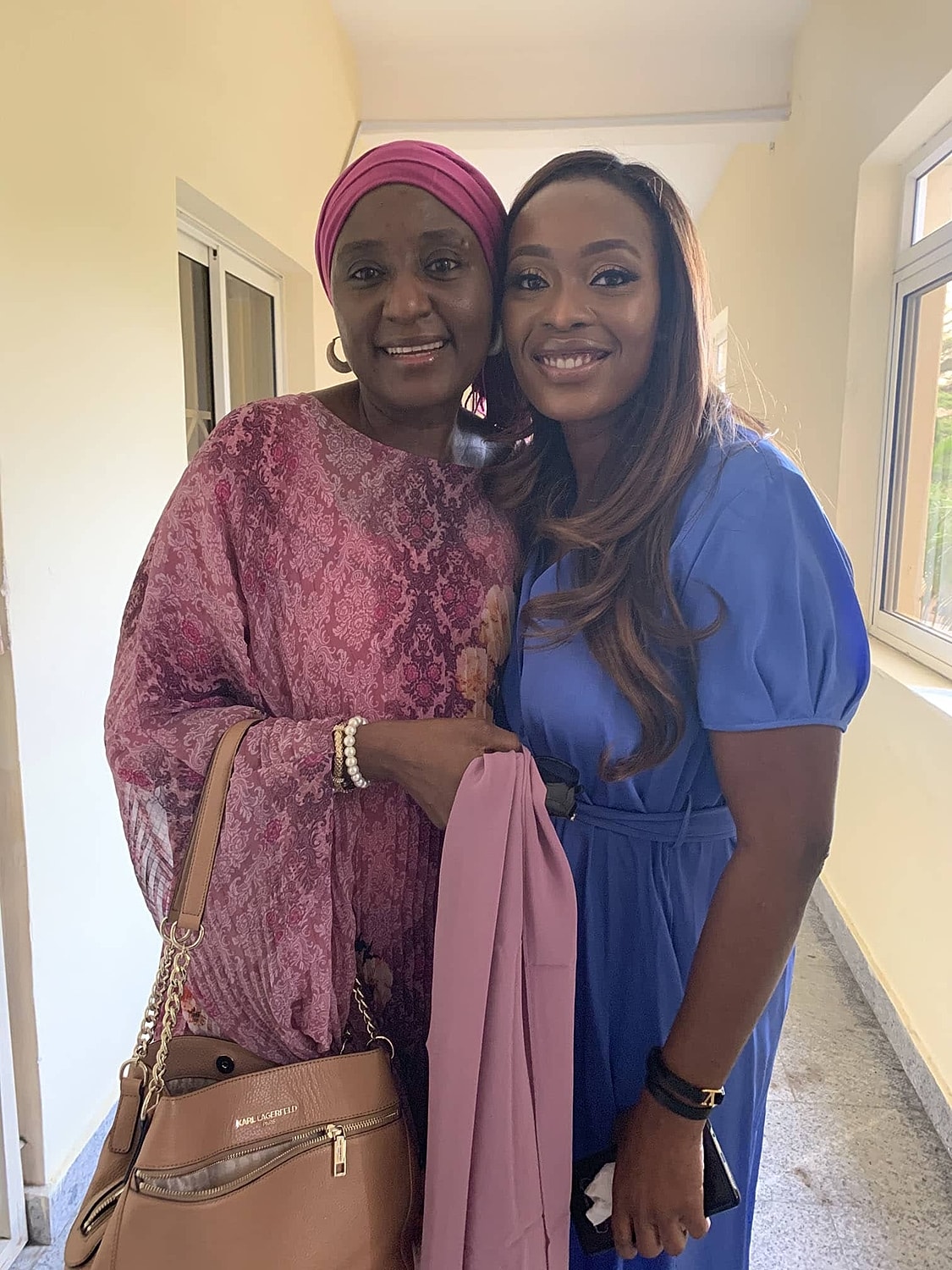 Two women smiling together in a bright setting.