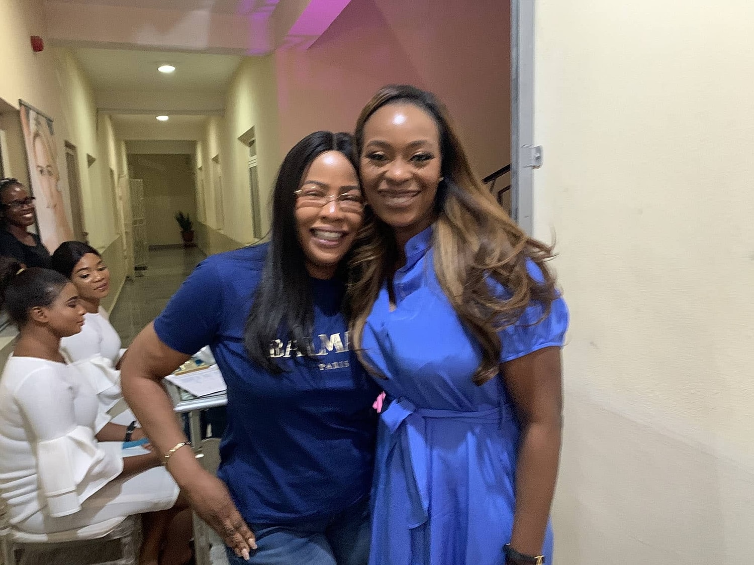 Two women smiling at an event indoors.