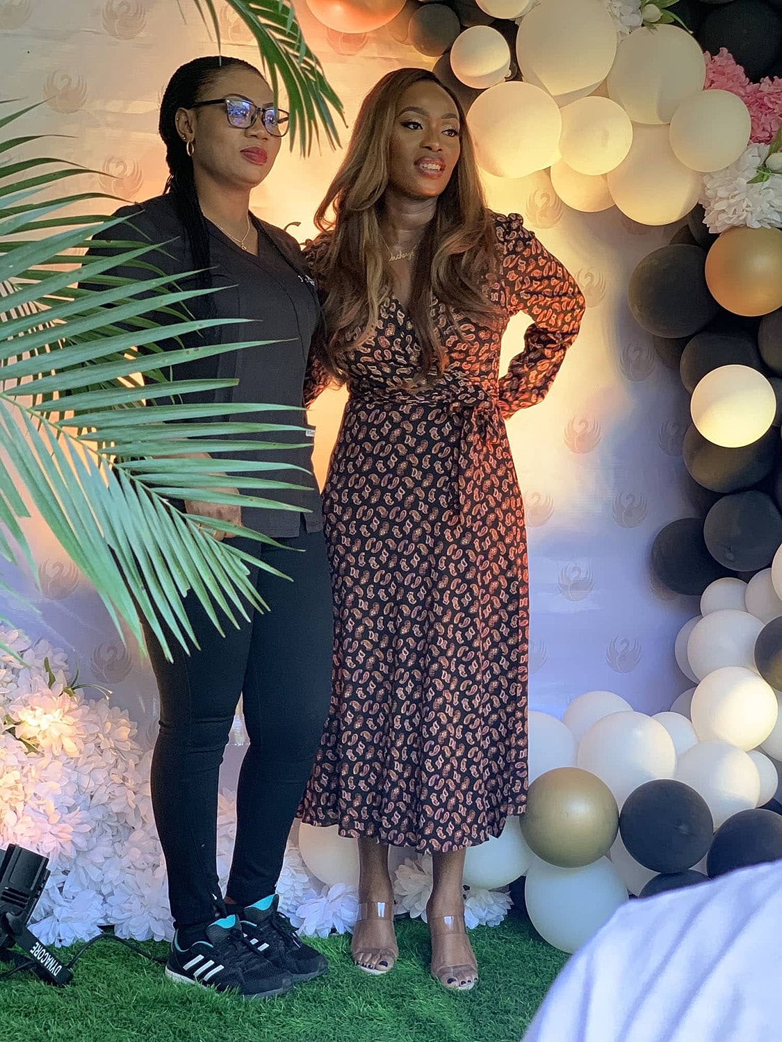 Two women posing at an event backdrop.
