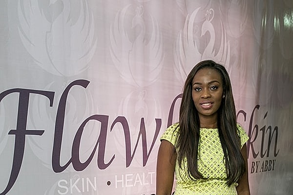 Woman standing in front of Flawless Skin backdrop.
