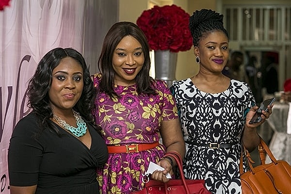Three women smiling at a social event.