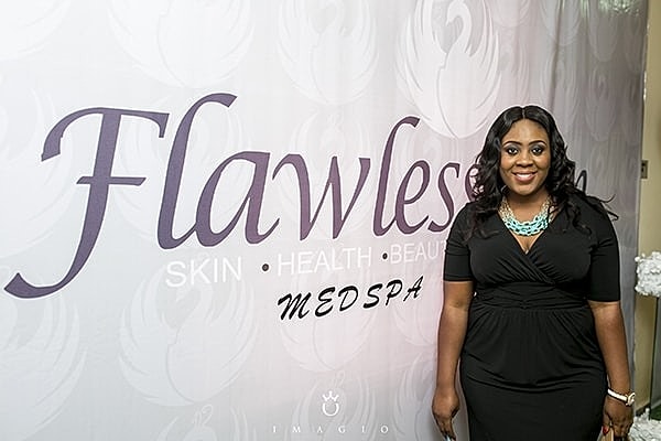 Person standing by Flawless MedSpa backdrop.