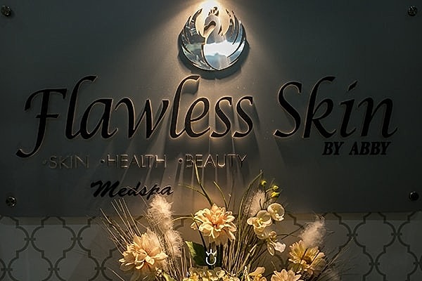 Flawless Skin by Abby sign with decorative flowers.