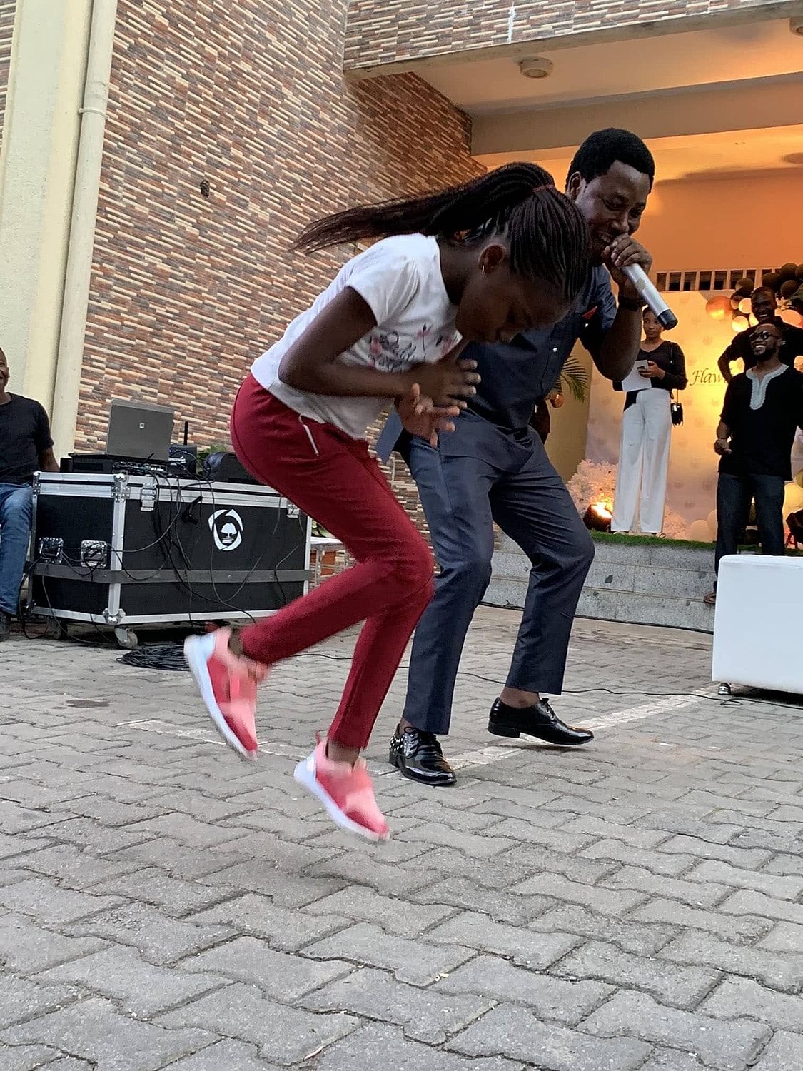 Child dancing with adult performer at event.