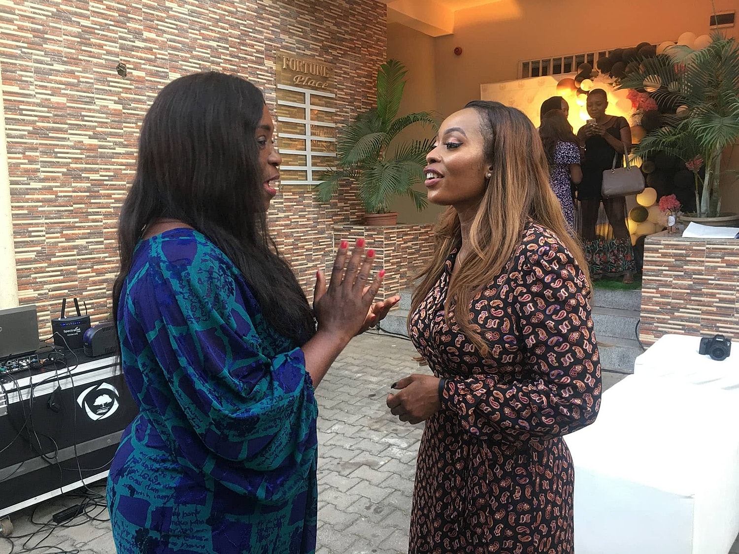 Two women chatting at an event outdoors.