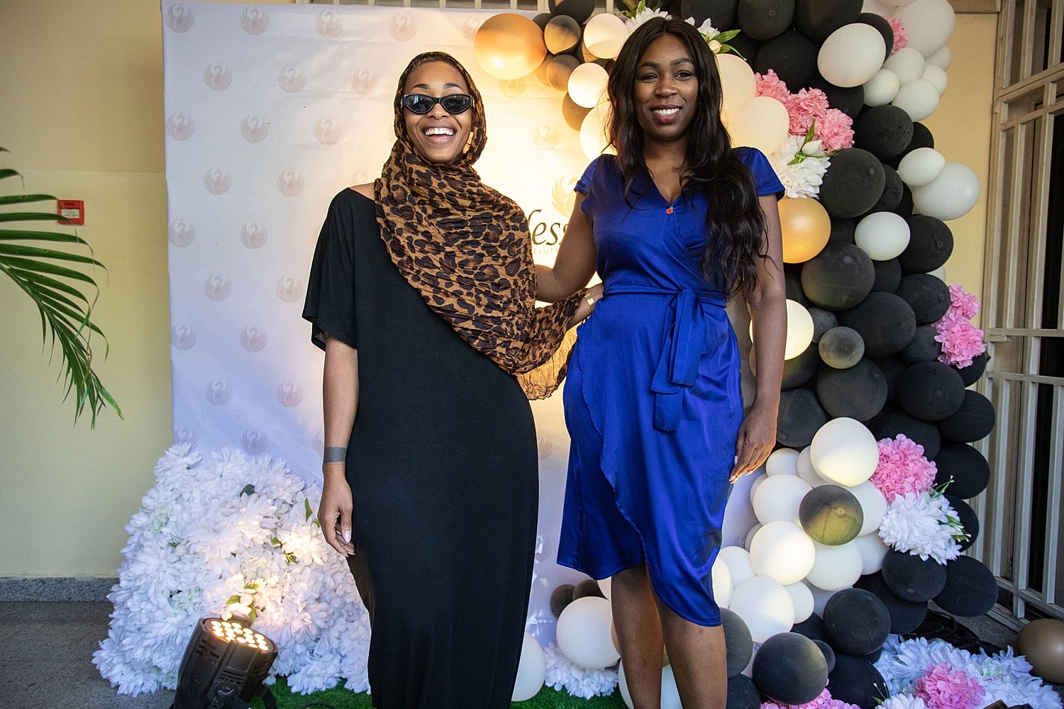 Two women smiling at a festive event backdrop.
