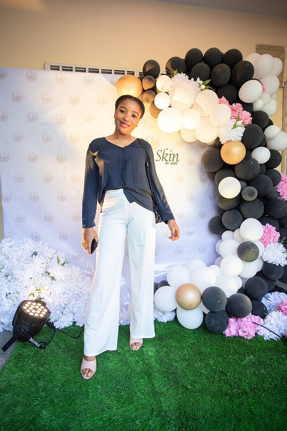 Person posing at a festive balloon backdrop.