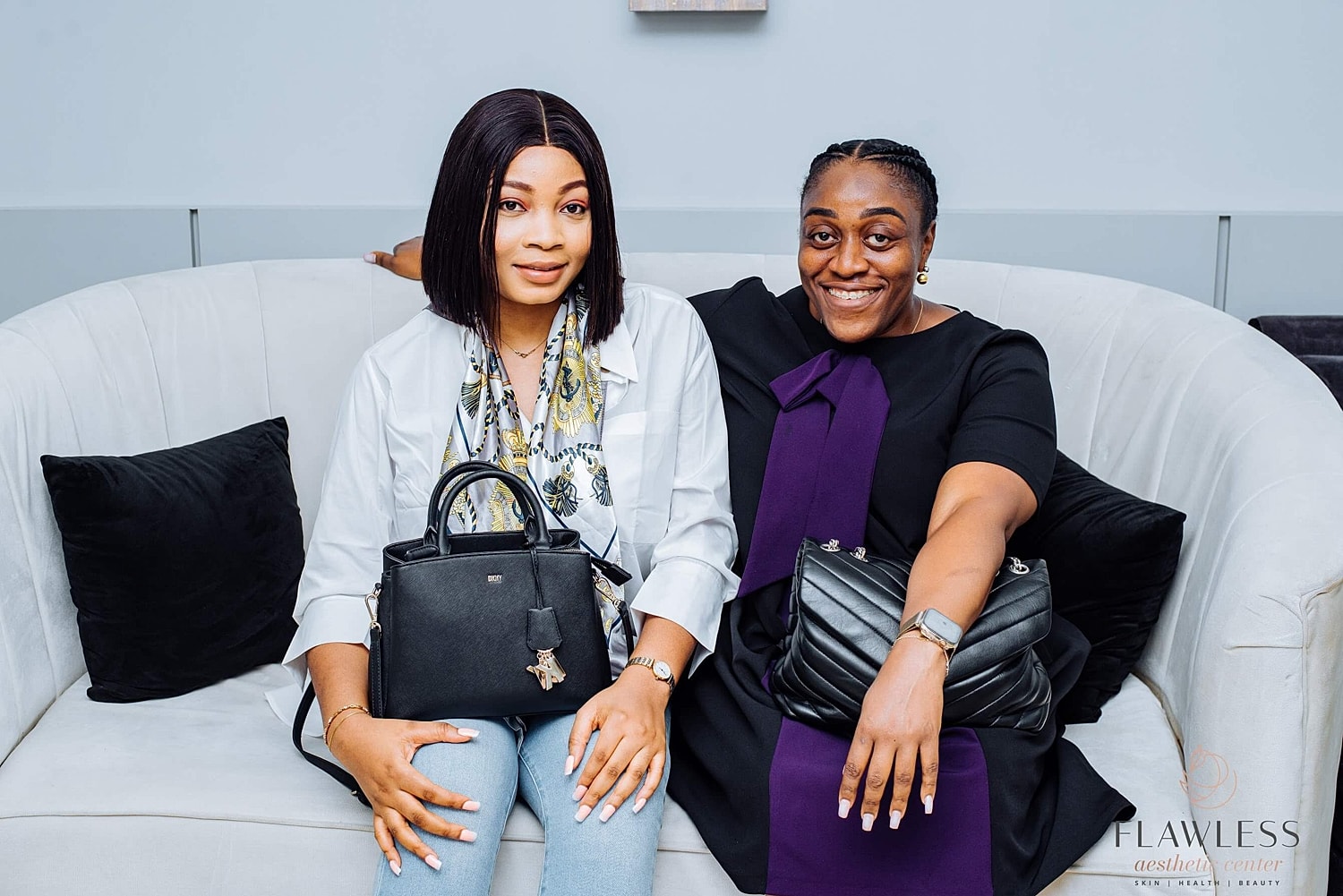 Two women smiling on a stylish couch.