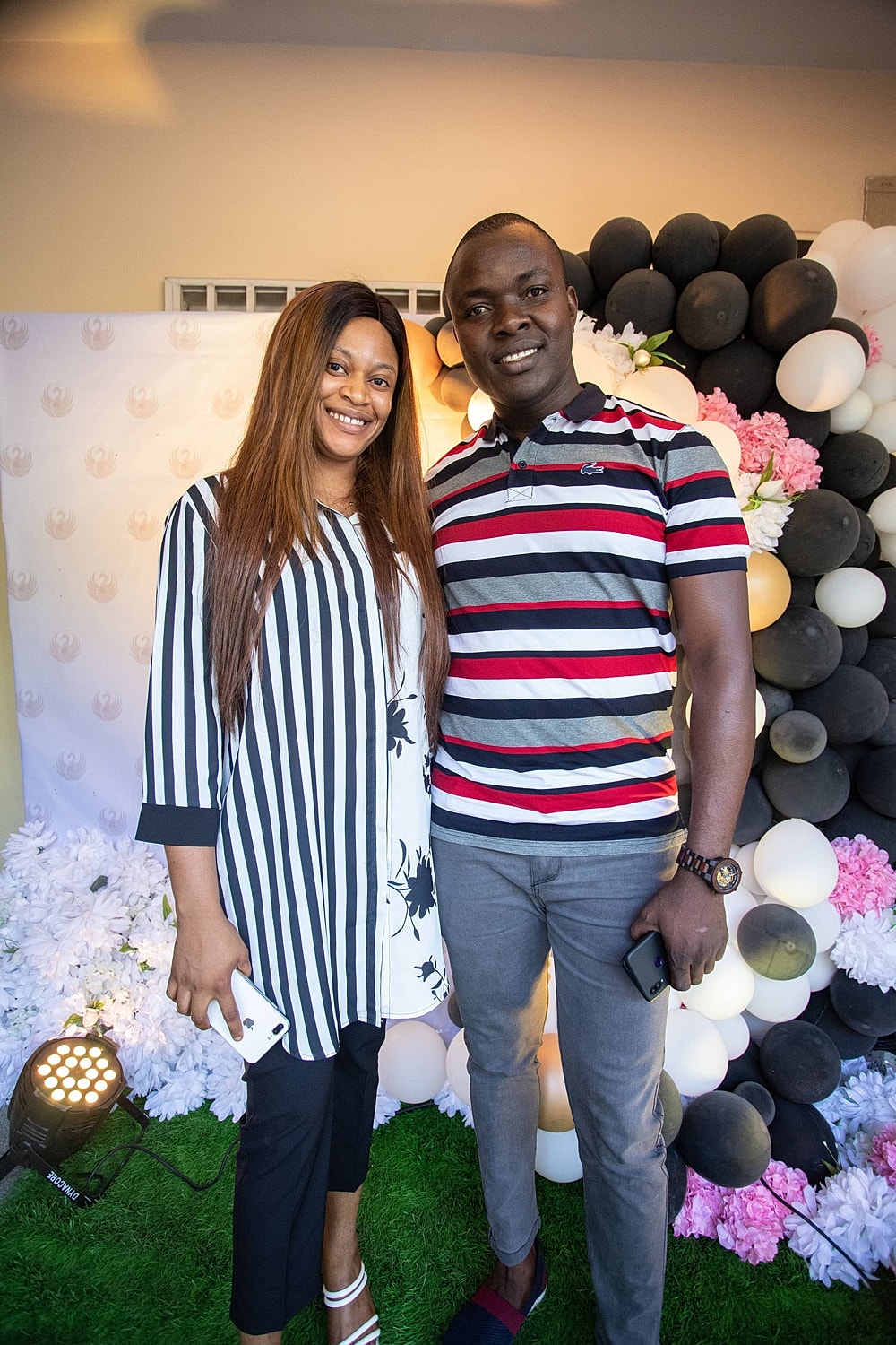Couple posing at an event with floral backdrop.