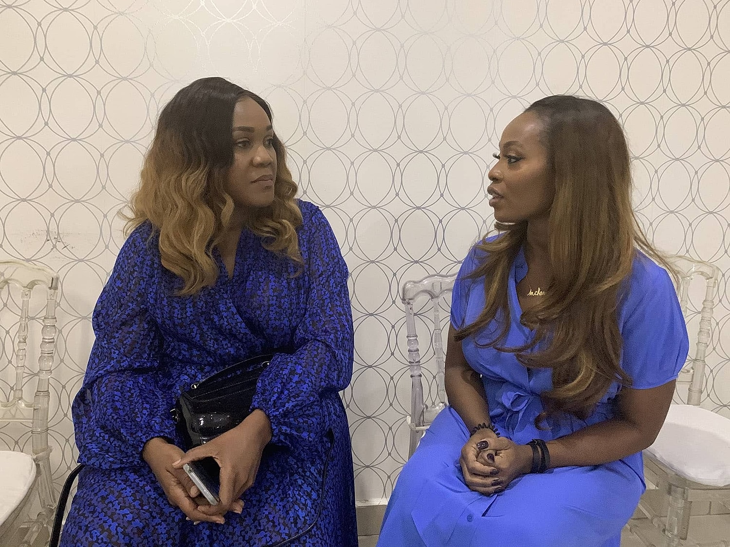 Two women in conversation, both wearing blue.