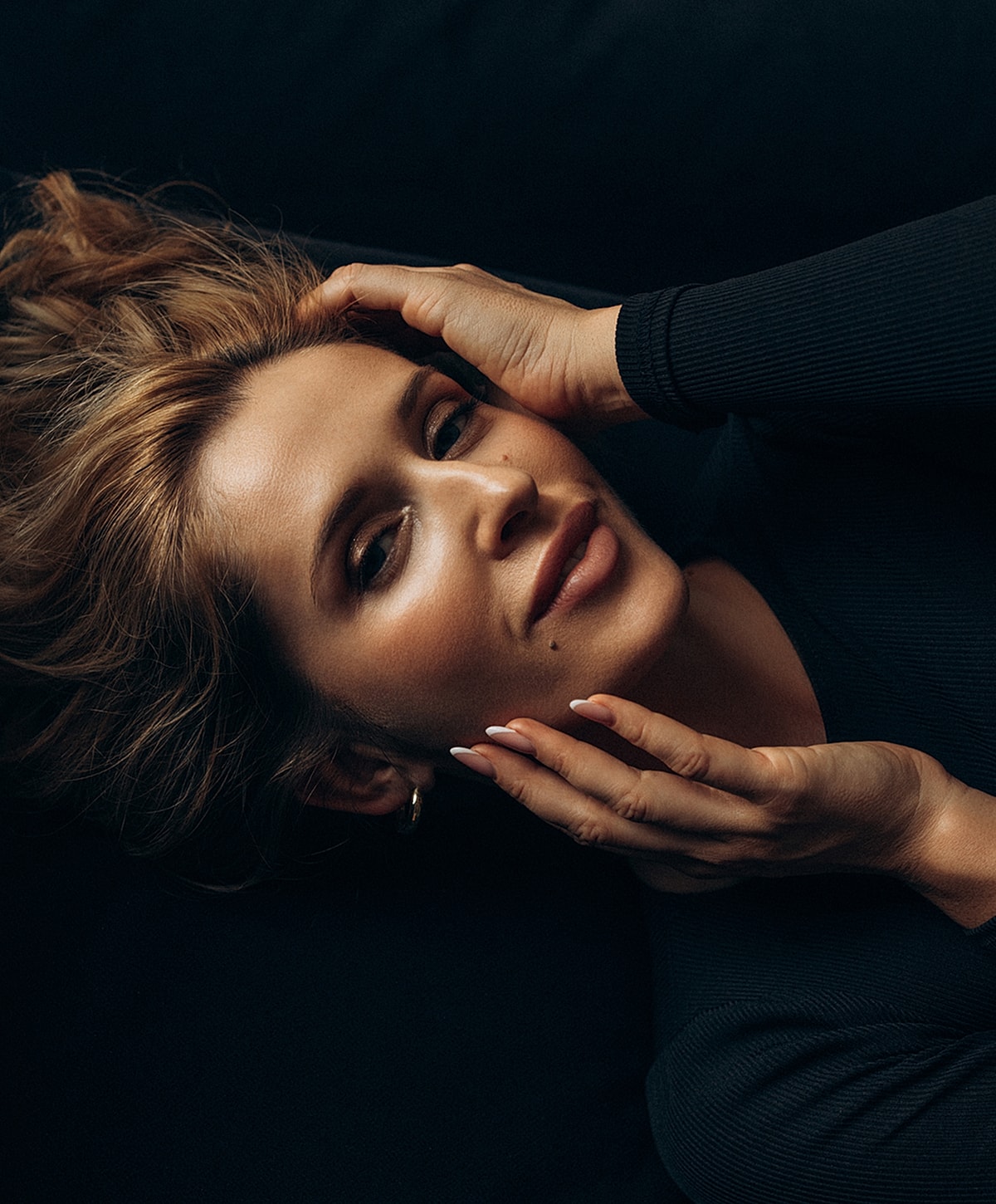 Abuja Non-Surgical Facelift model resting with hands in her hair.