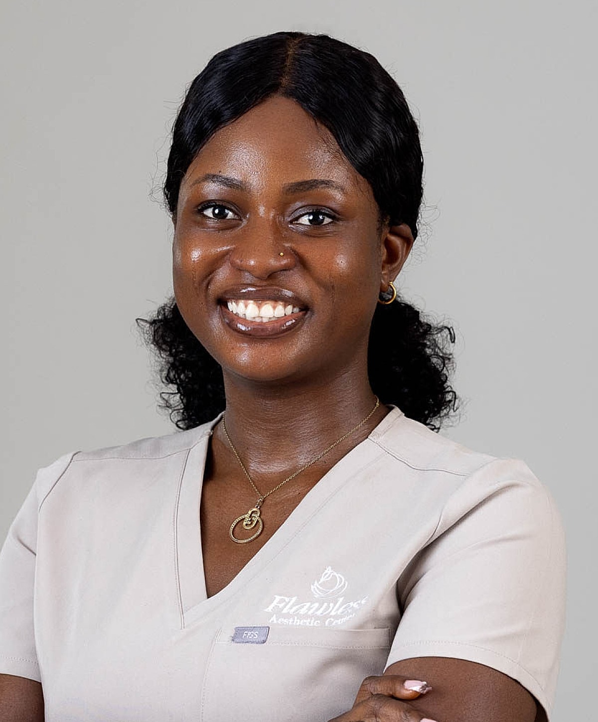 Smiling professional in aesthetic clinic uniform.