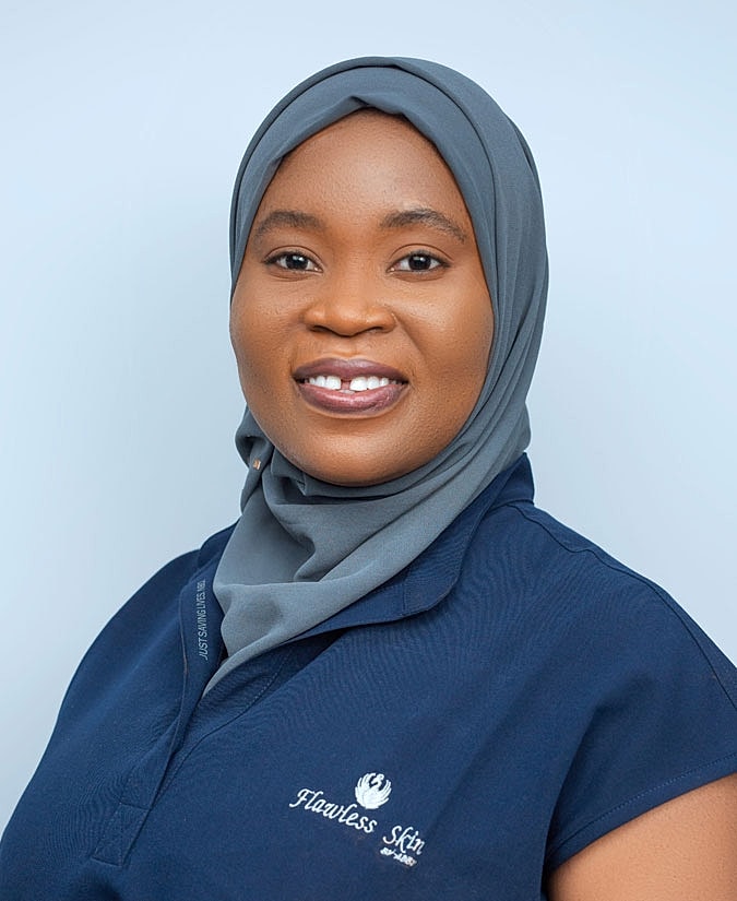 Smiling woman wearing a hijab and uniform.