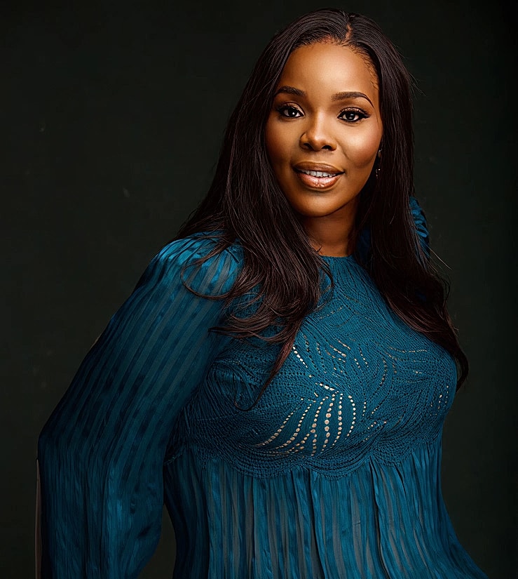 Woman in elegant blue attire, smiling confidently.