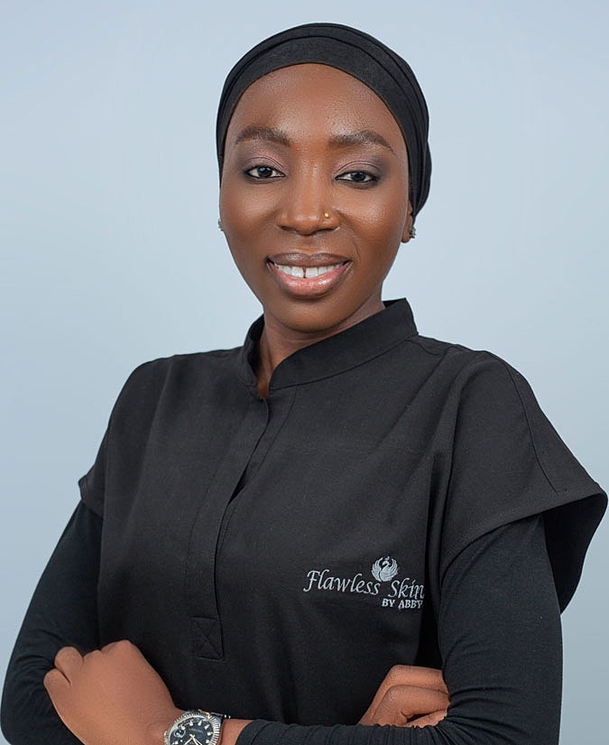 Woman in professional attire with skincare branding.
