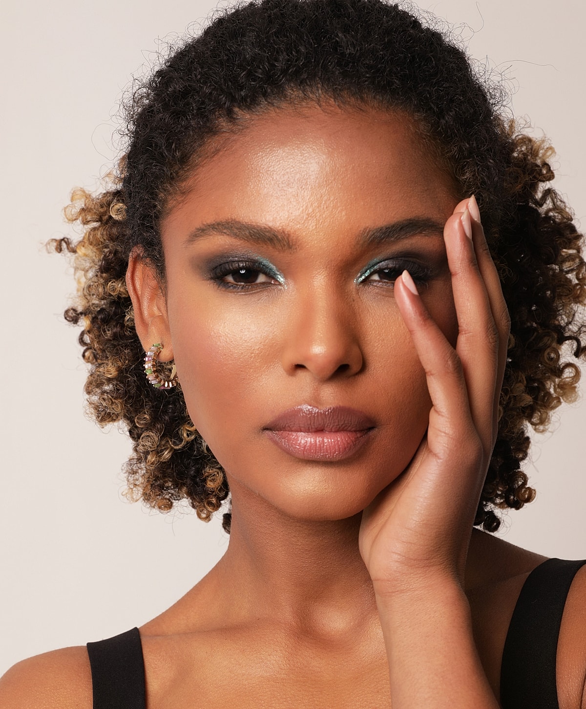 Abuja Facial Treatments model with curly hair and glamorous makeup.