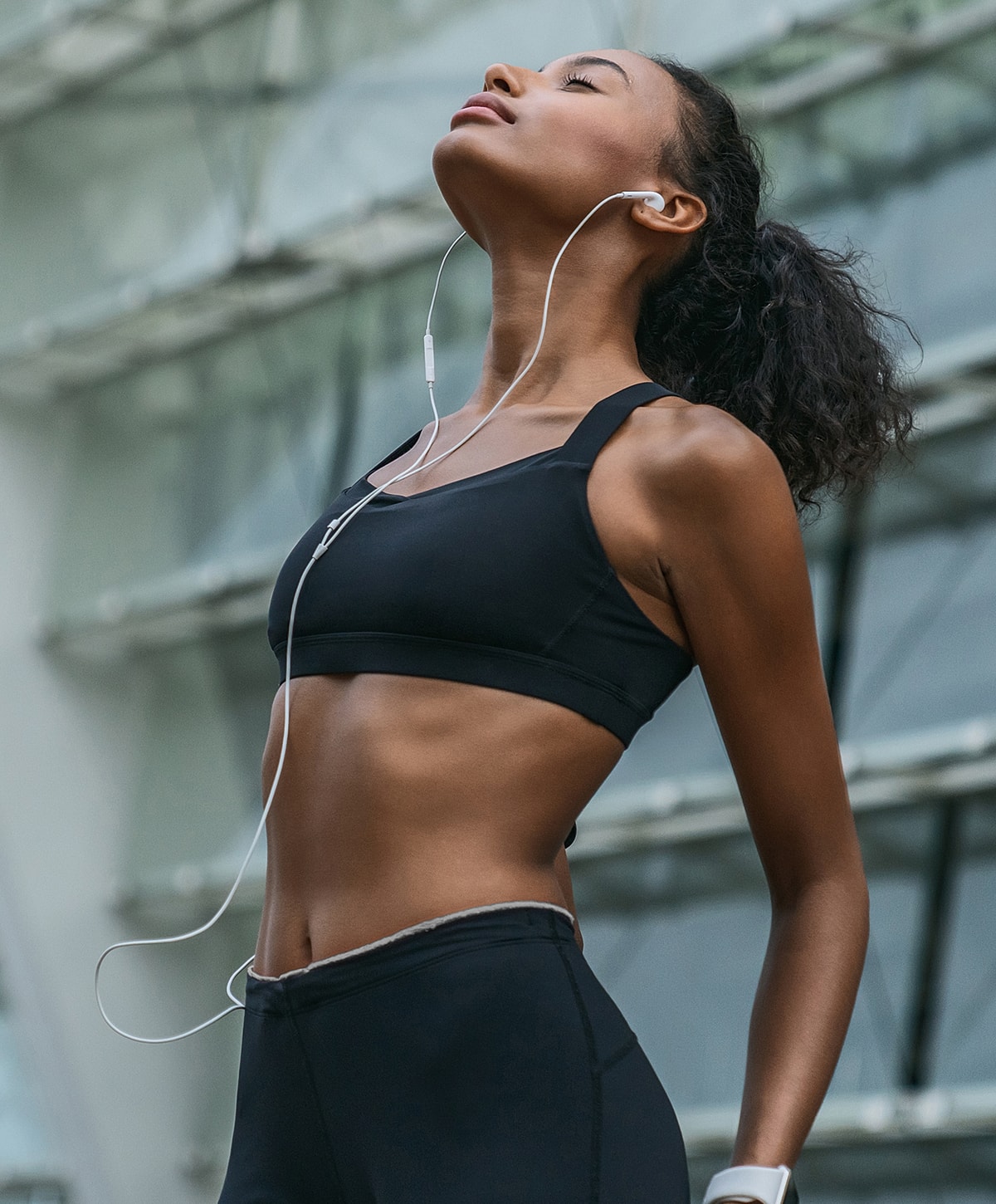 Abuja Regenerative Medicine model with earbuds in athletic wear, looking up.