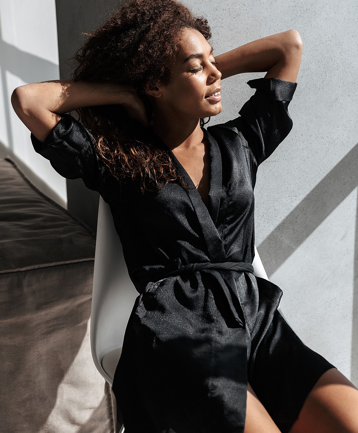 Abuja Female Wellness Model in black outfit relaxing in sunlight.