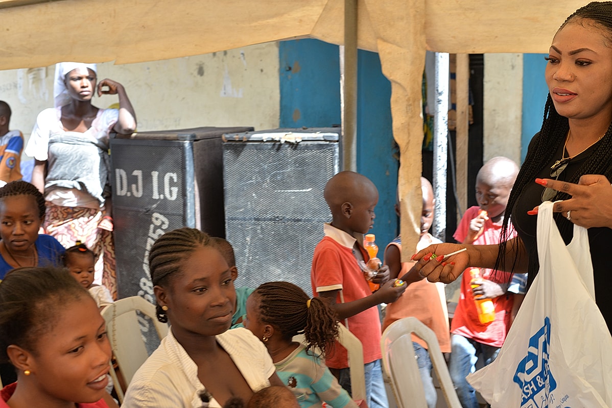 Mother holding a baby in a crowded setting.