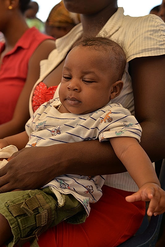 Baby resting in a caregiver's lap.