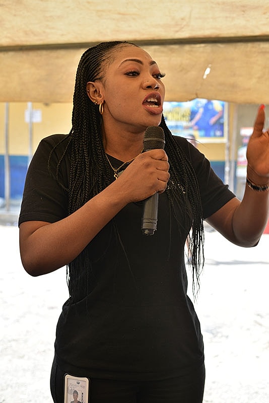 Woman speaking into a microphone at event.