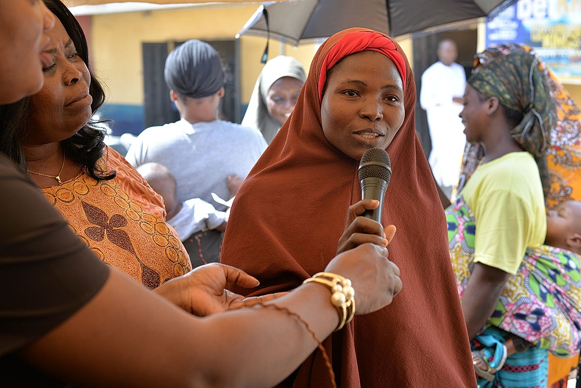 Woman speaking into a microphone at an event.