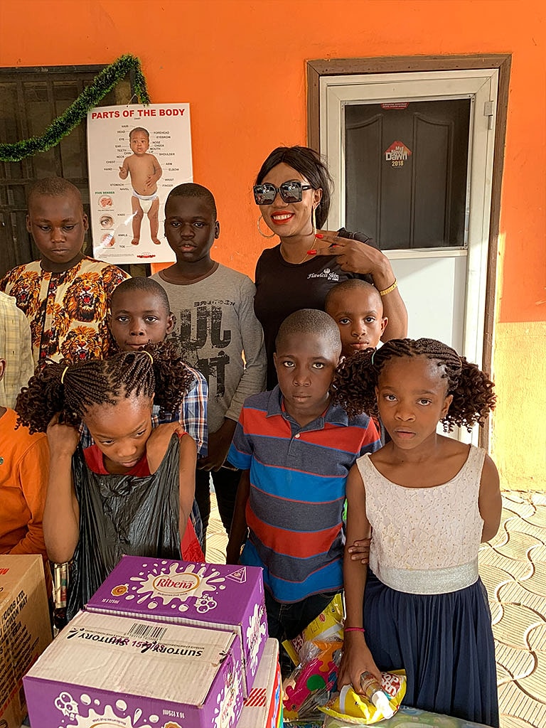 Children posing with a smiling adult in a classroom.