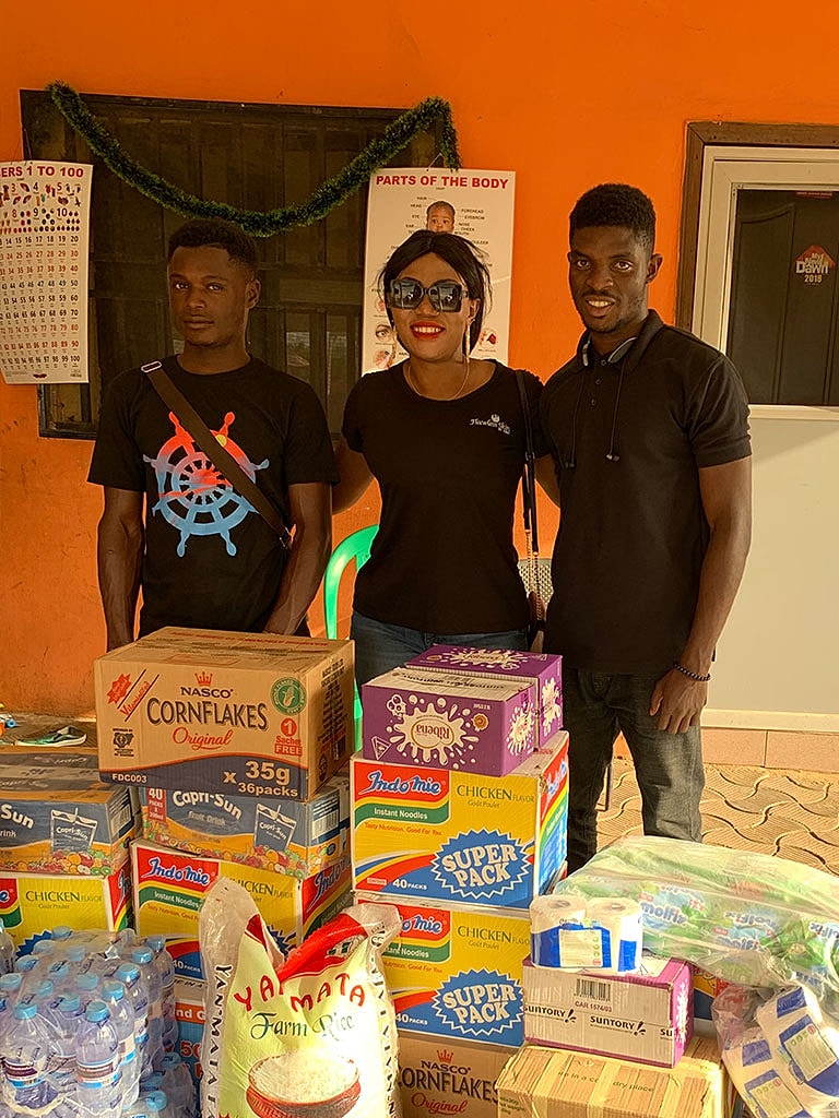 Three people displaying food items for donation.