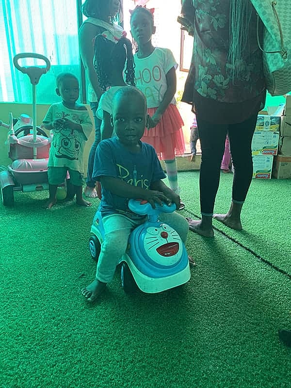 Child riding a toy vehicle among other kids.