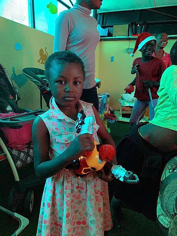 Child holding toys in colorful playroom setting.