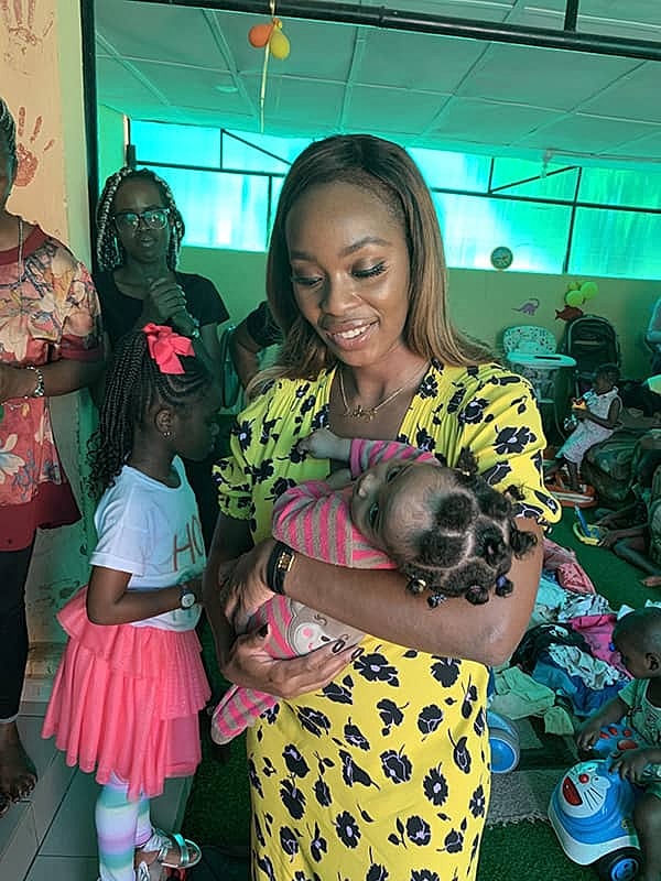 Woman holds a baby in colorful setting.
