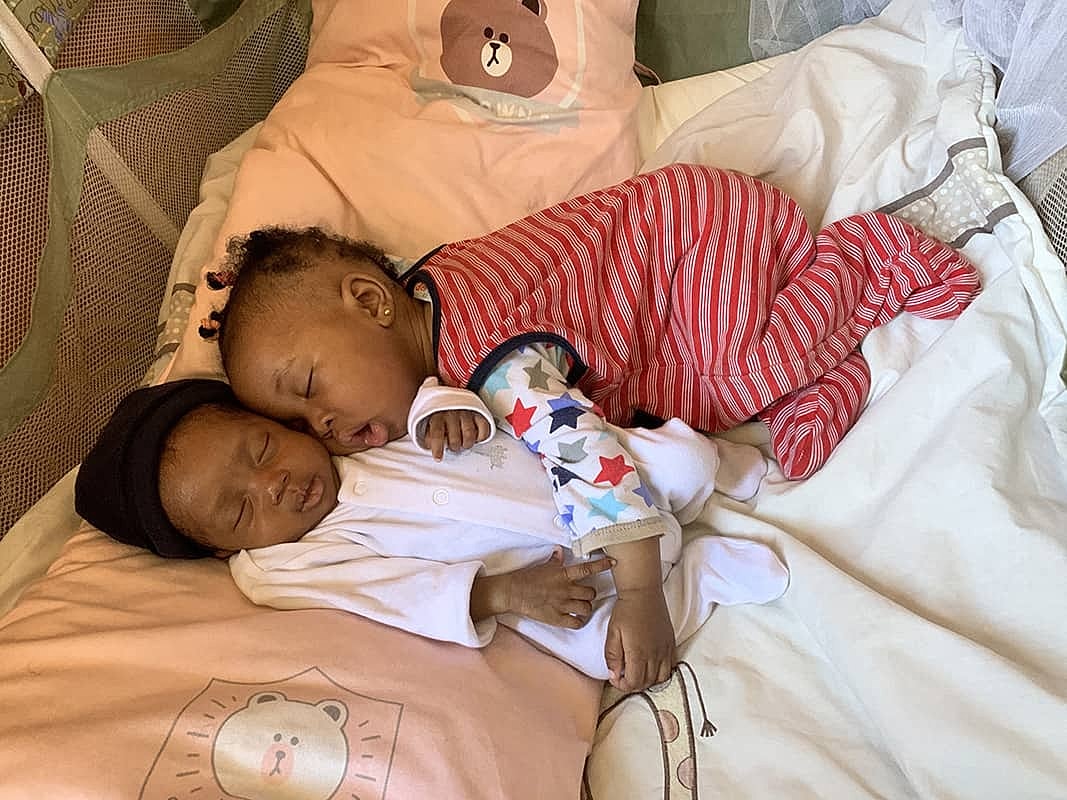 Two babies sleeping peacefully on a bed.