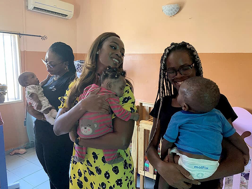 Women holding infants in a warm setting.