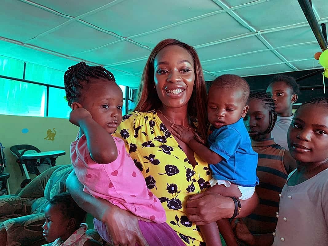Smiling woman holding children in vibrant setting.