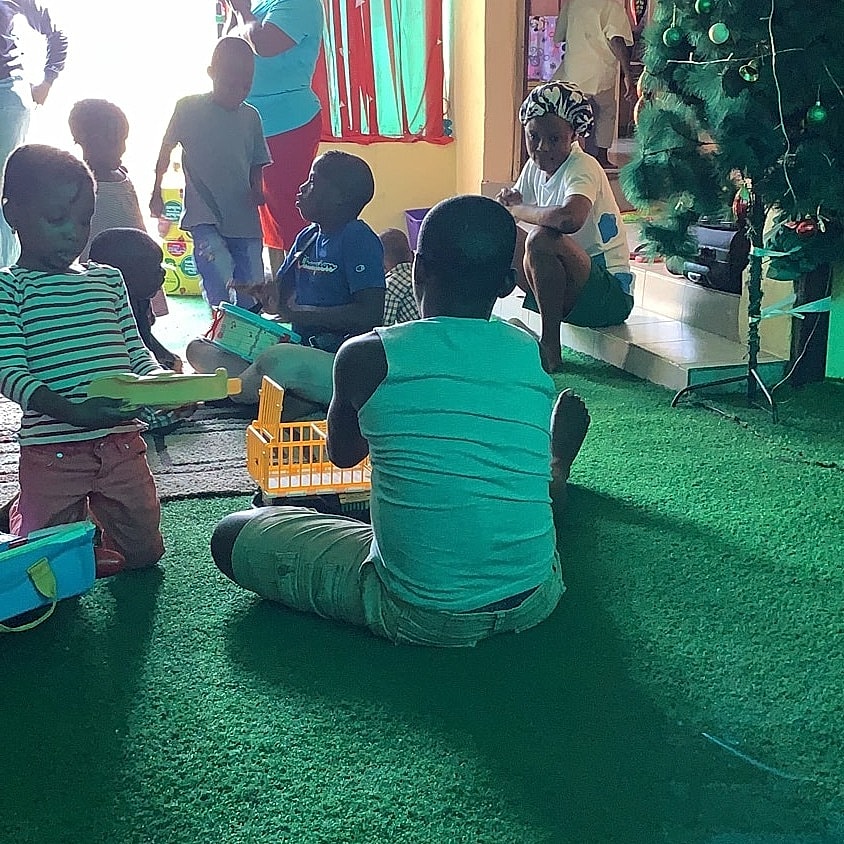 Children playing indoors near a Christmas tree.