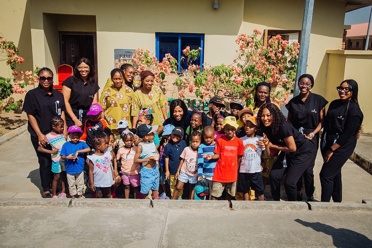 Group photo with children and caregivers outdoors.