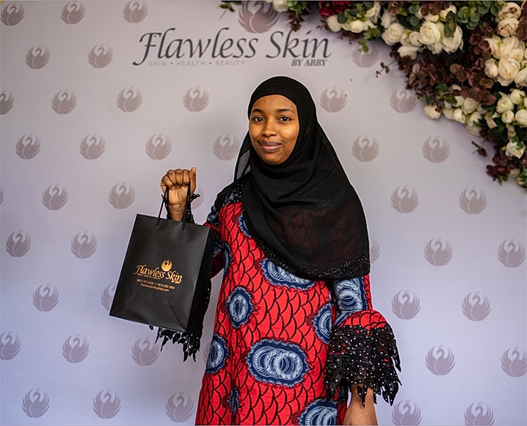 Woman holding Flawless Skin shopping bag, smiling.