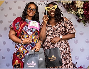 Two women posing with props and gift bags.