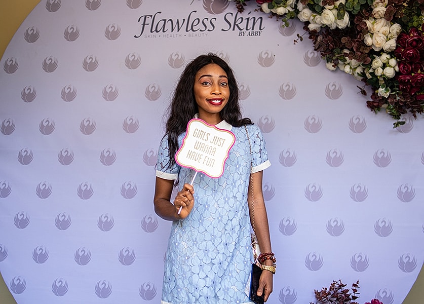 Woman holding sign at Flawless Skin event.