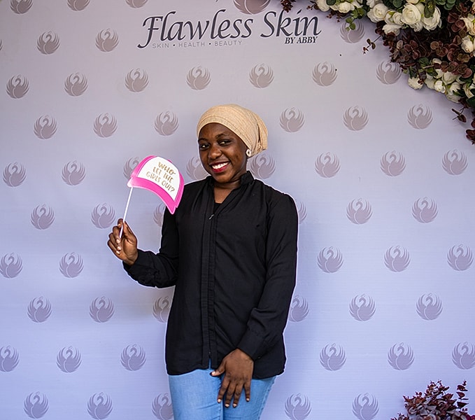 Smiling woman holding sign at beauty event.