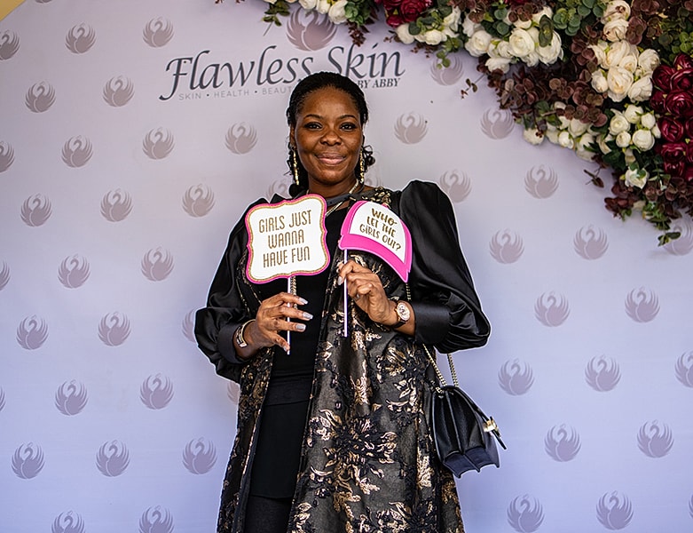 Woman holding fun signs at event backdrop.
