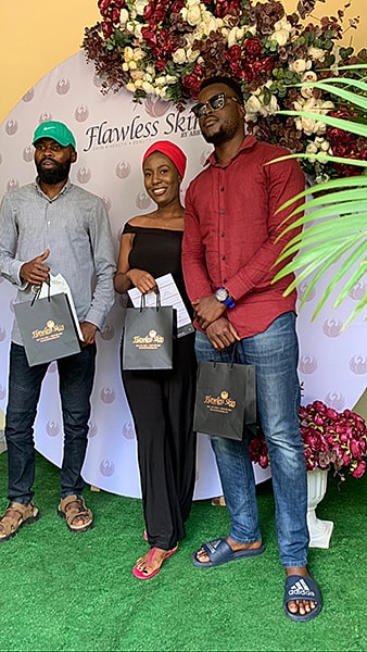 Three people posing with gift bags at event.