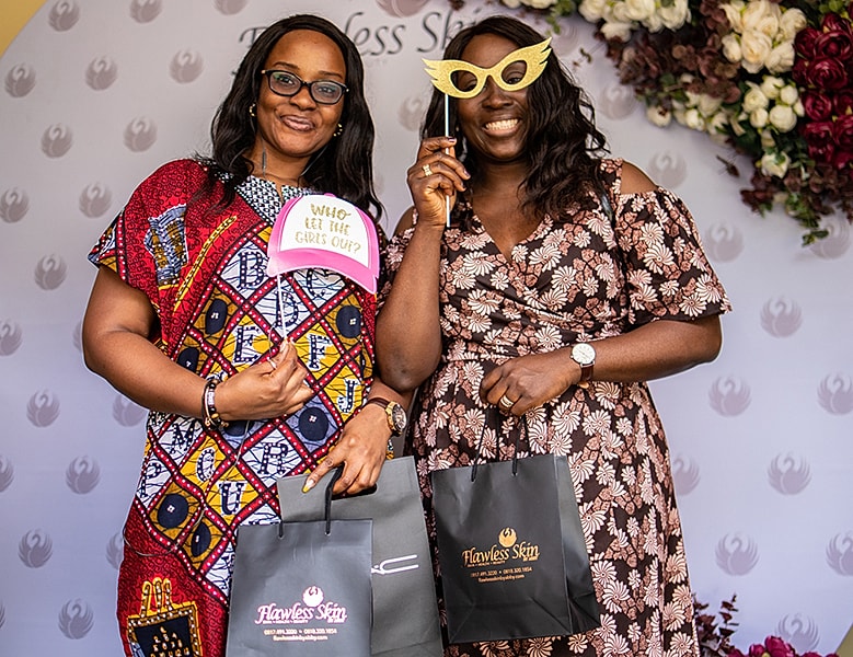 Two women enjoying an event with playful props.