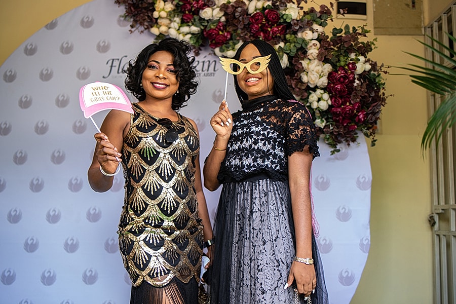 Two women posing with props at an event.