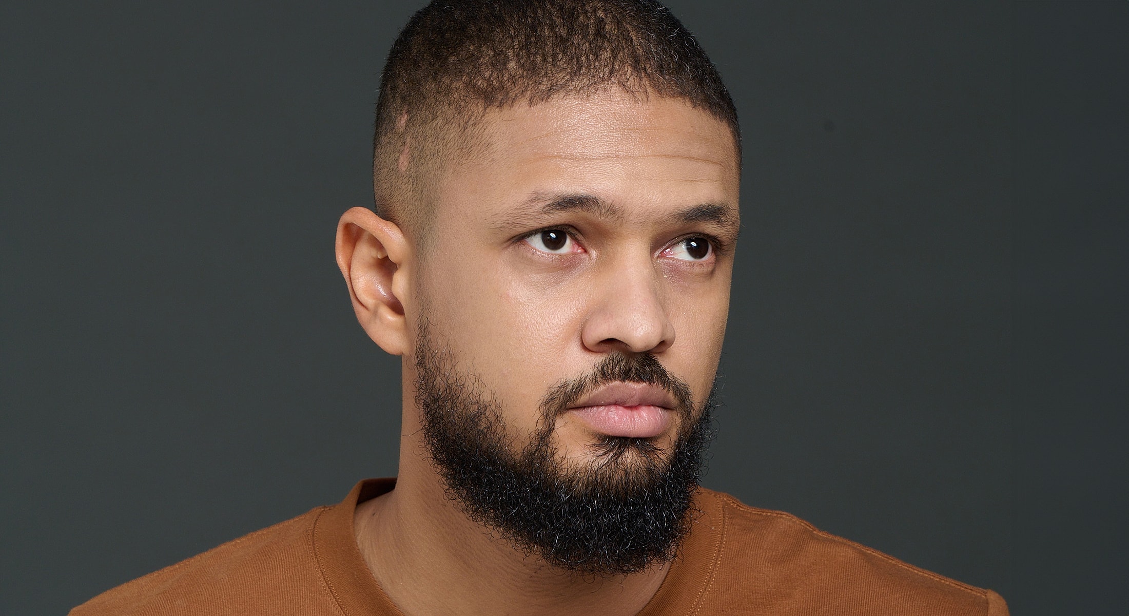 Abuja Procedures For Men model with beard and short hair, neutral expression.