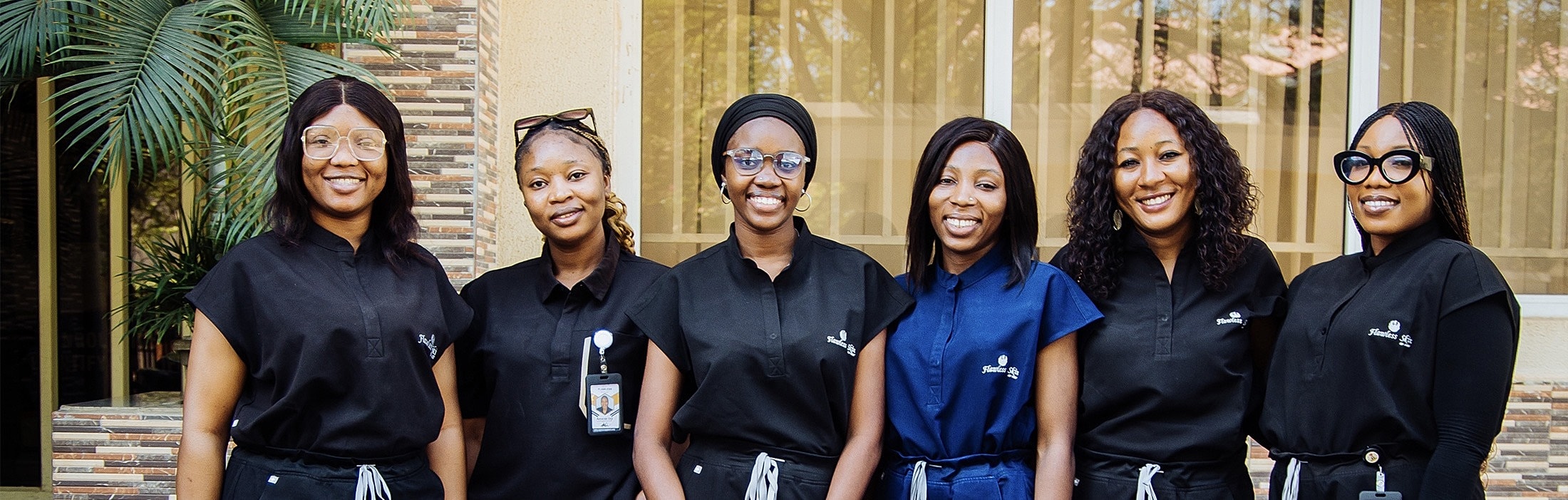 Six professionals posing in front of a building.