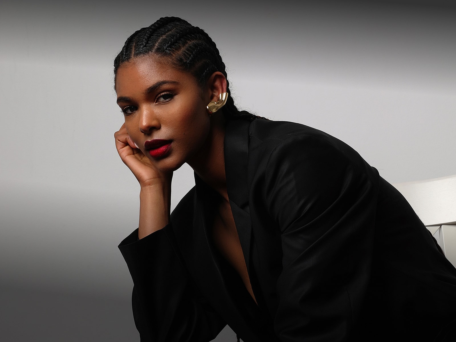 Woman in black blazer with braided hair.