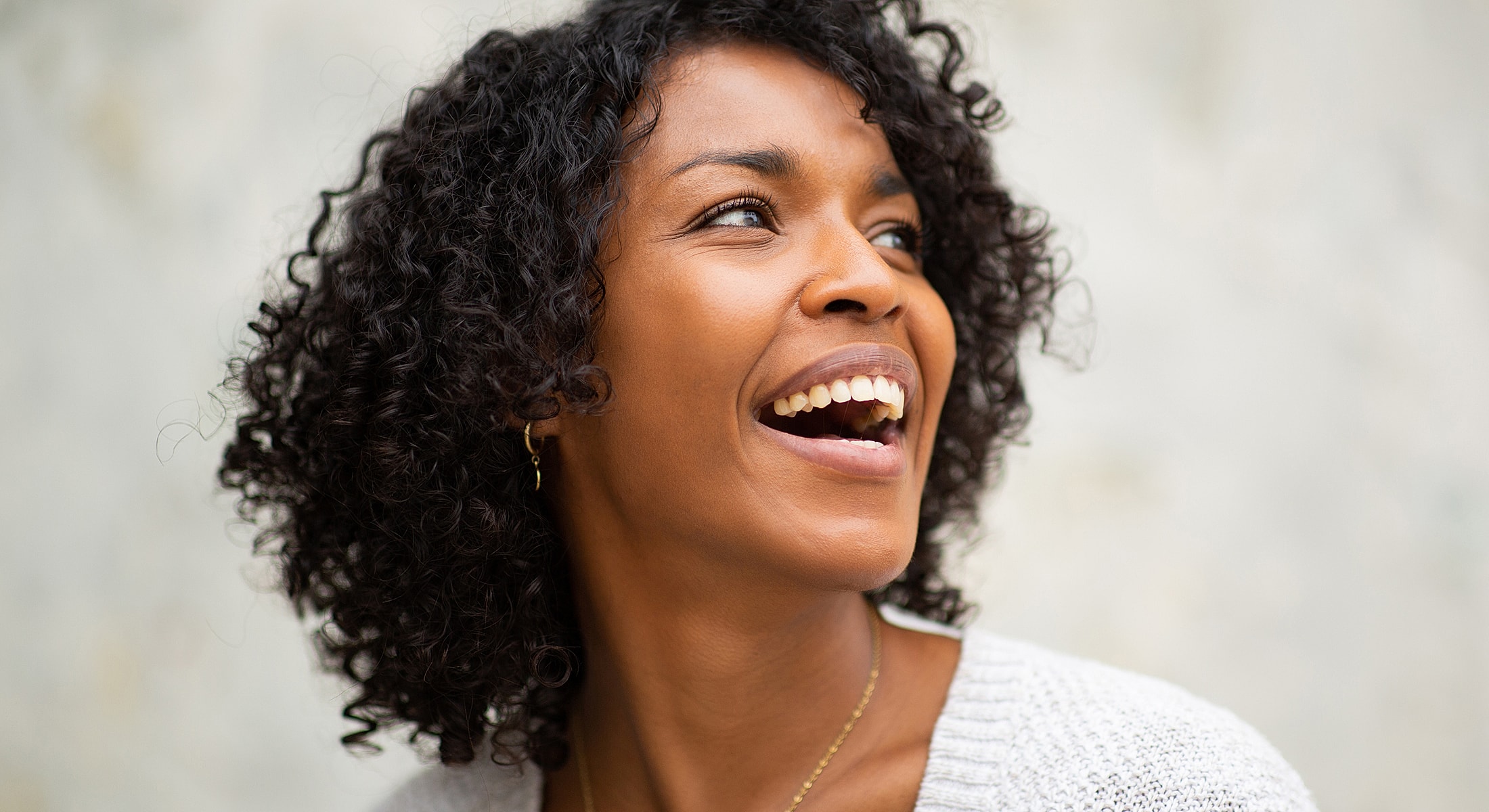 Smiling woman with curly hair against neutral background.